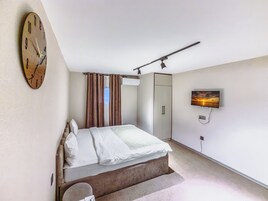 Een slaapkamer met een bed, een klok, een televisie en een kledingkast.