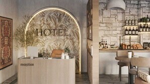 A hotel reception area with a modern design, featuring a reception desk, a wall-mounted sign, a bar area with shelves of bottles, and a seating area with a table and chairs. - Dastan Baku Hotel (Baku)