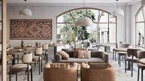 A modern living room with a large window, a patterned rug, and a sofa with ottomans. - Dastan Baku Hotel (Baku)