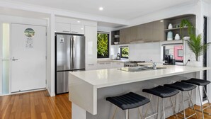 A modern kitchen with a large island, stainless steel appliances, and bar stools.