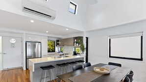 A modern kitchen with a central island, bar stools, and a dining table with chairs.
