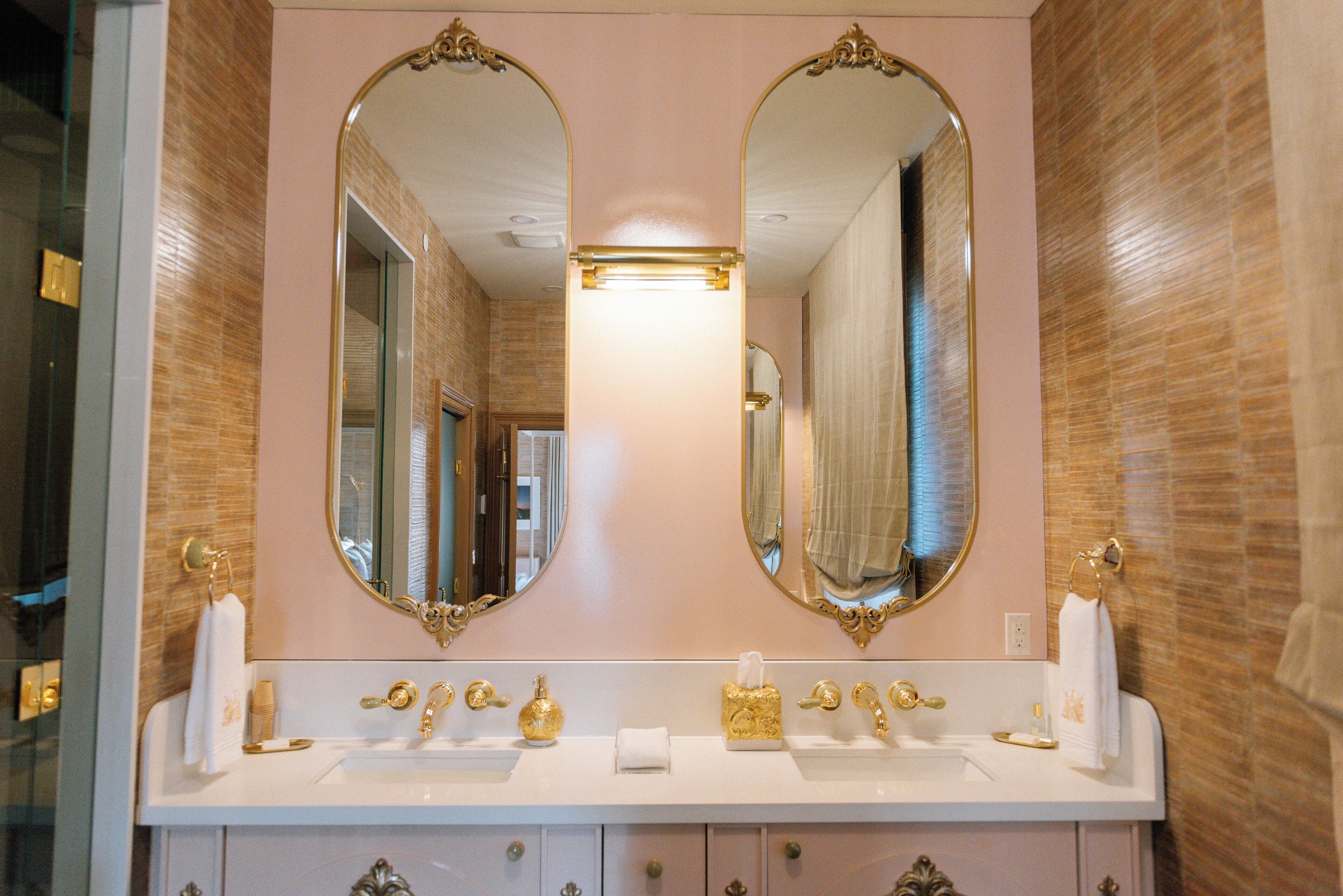A bathroom with a double vanity, two large mirrors, and a light above the sink.
