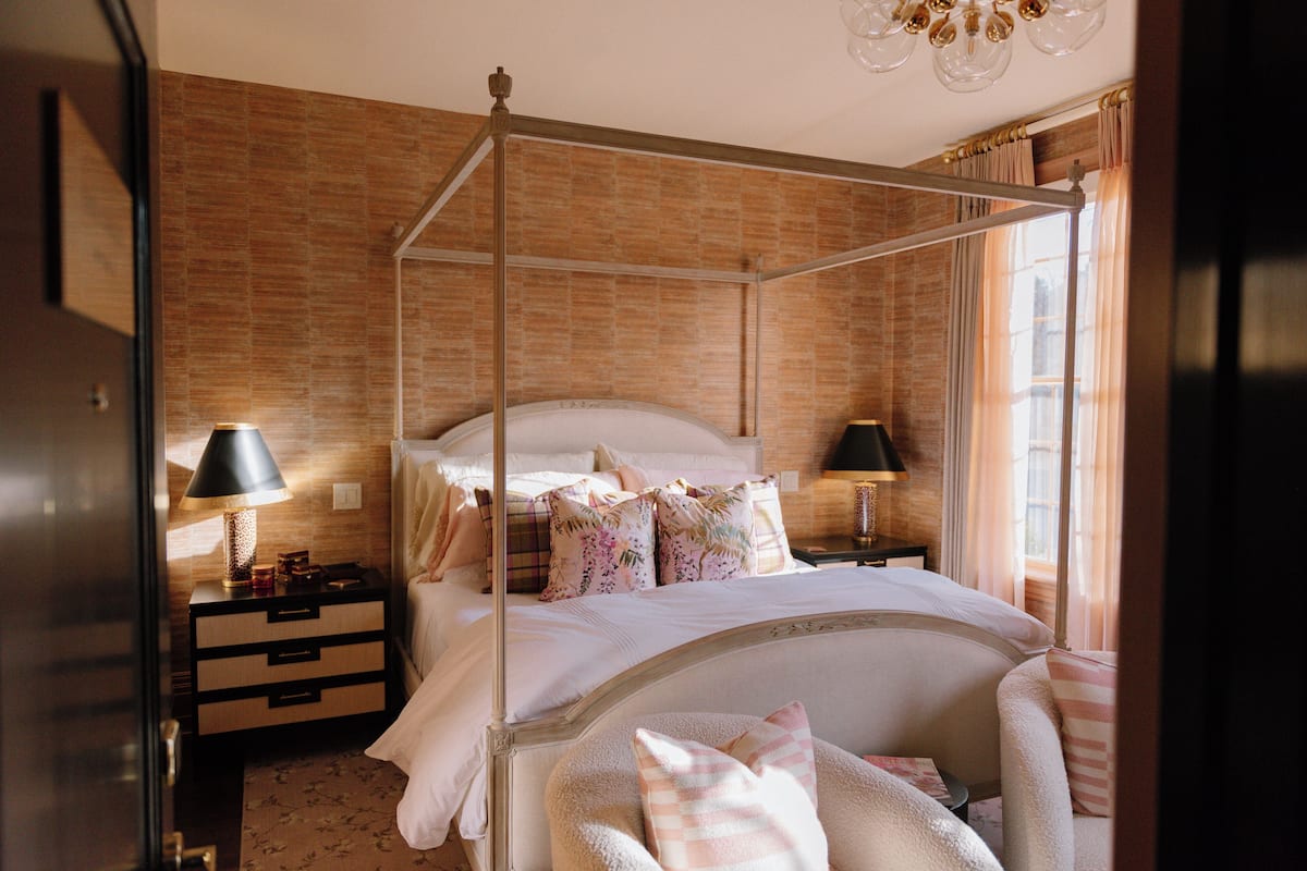 A four-poster bed with a canopy, a bedside table with a lamp, and a nightstand with drawers.