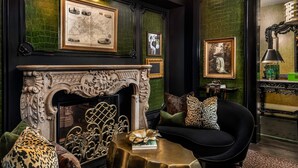 A luxurious room with a fireplace, a sofa with leopard print cushions, and a green textured wall. - The Scotsman Hotel (Niagara-on-the-Lake)