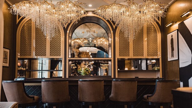 A bar area with multiple seating and ornate chandeliers. - The Scotsman Hotel (Niagara-on-the-Lake)