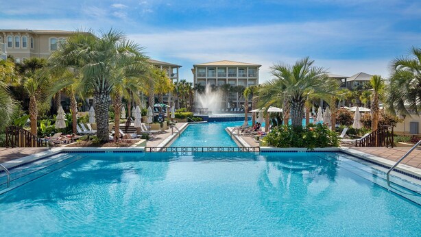 A swimming pool with palm trees and lounge chairs, surrounded by buildings. - 30A ~ 3 Primary Suites ~ Next to Community Pool (Inlet Beach)