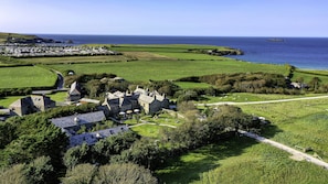 A coastal village with stone buildings, a grassy landscape, and a view of the sea. - THE PIG at Harlyn Bay - Cornwall (Padstow)