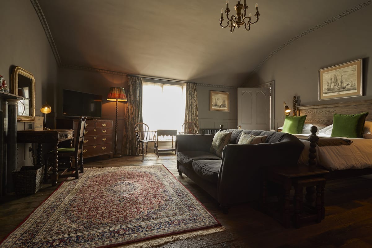 A cozy room with a large window, a sofa, a small table, and a TV.