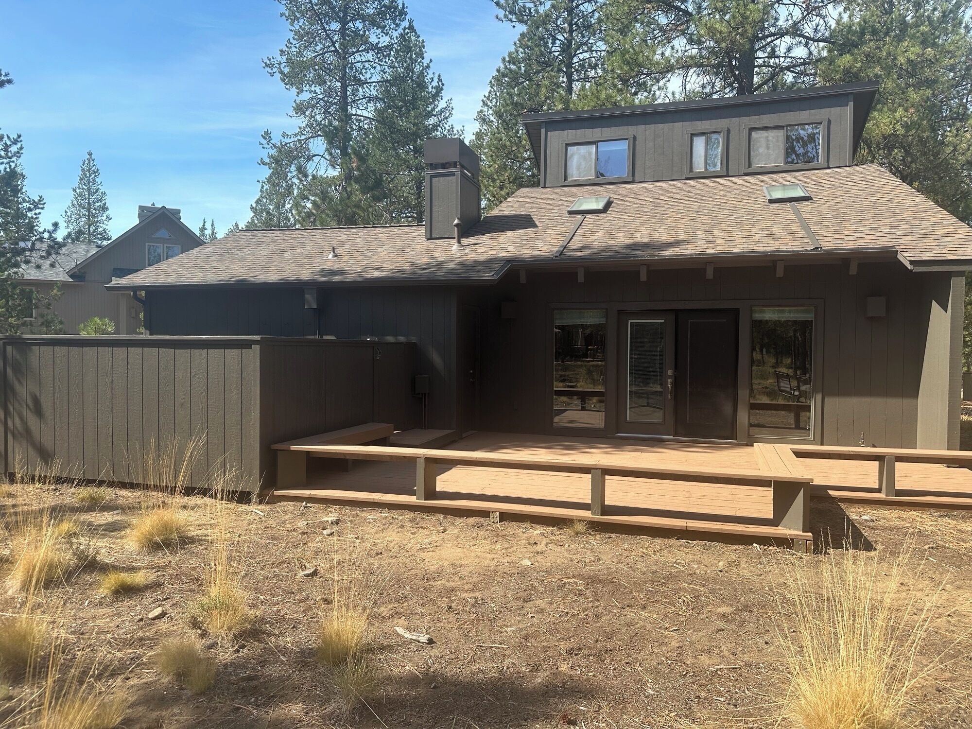 A modern house with a covered patio, a large window, and a chimney.