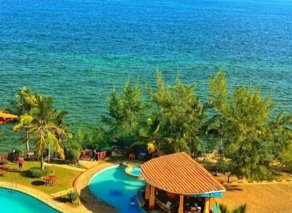 Un complexe hôtelier doté d’une piscine, de palmiers et d’une plage.