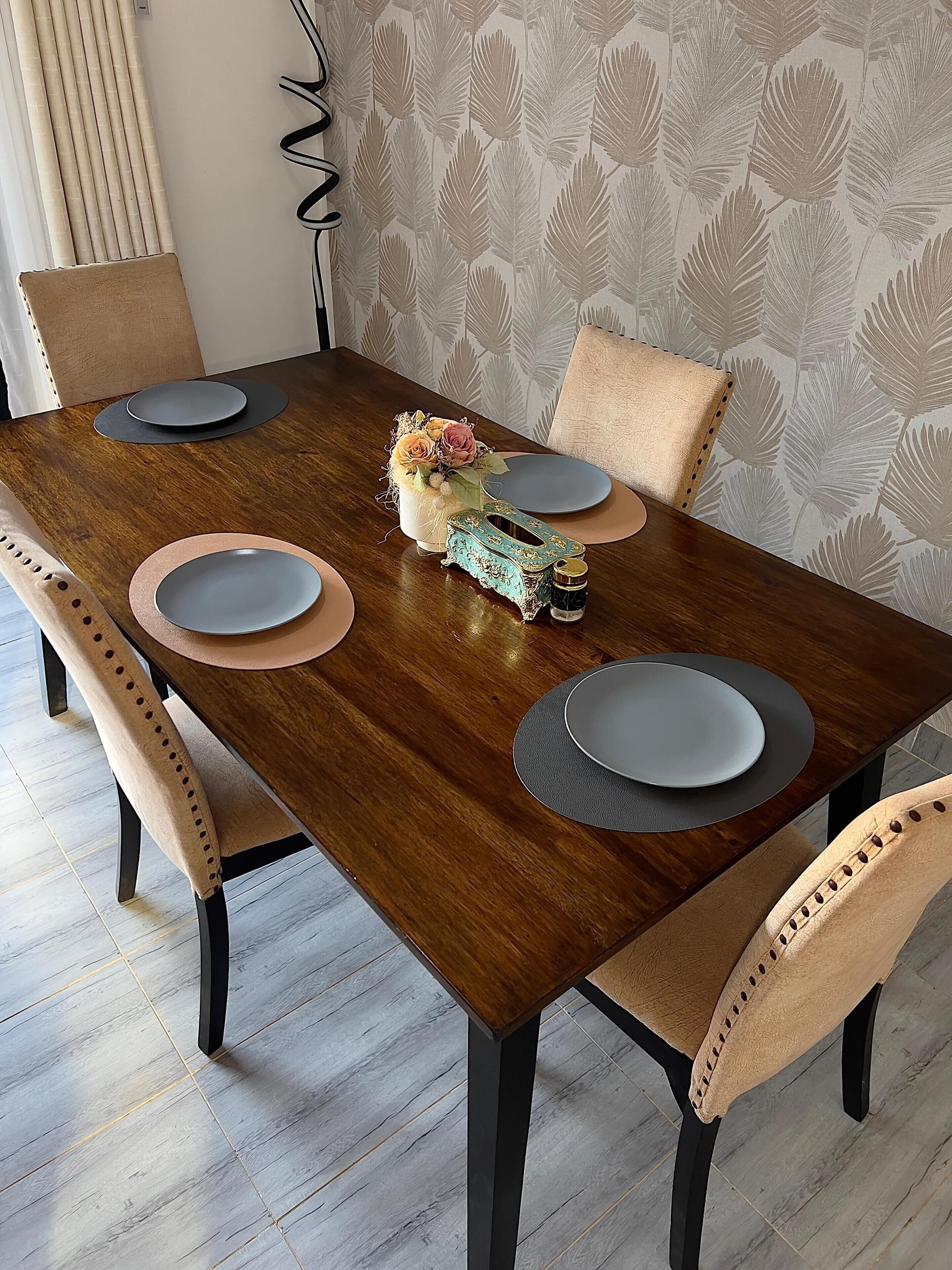 Una mesa de comedor con cuatro sillas, un jarrón con flores y un adorno sobre la mesa.