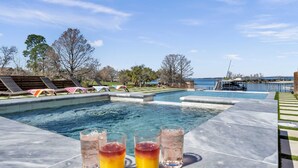 Ein Swimmingpool mit Liegestühlen und Blick auf das Wasser.