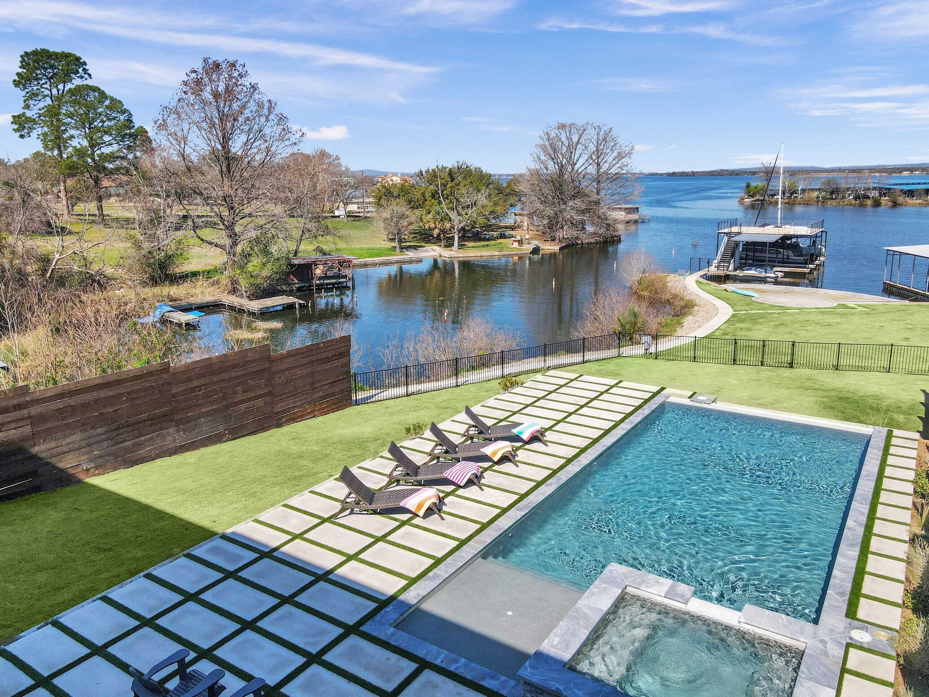 A swimming pool with a view of a lake and dock.