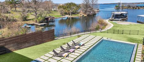 A swimming pool with a view of a lake and dock.