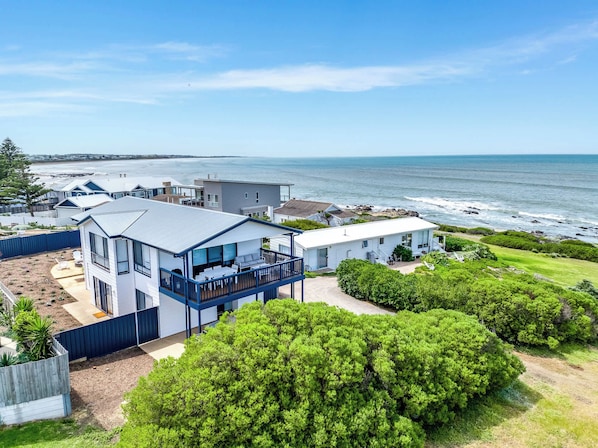 A coastal property with a large deck, a swimming pool, and a view of the ocean.