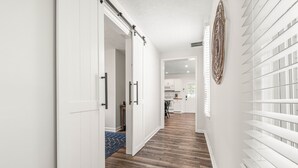 Käytävä, jossa on puulattia, valkoiset seinät ja liukuovi, joka johtaa keittiötilaan.