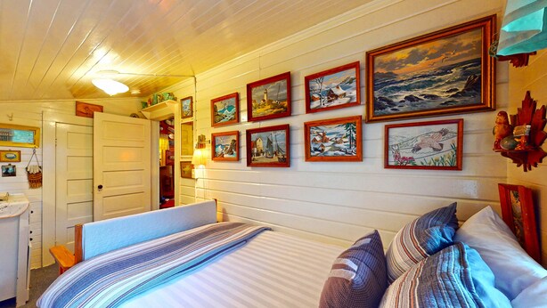 Um quarto aconchegante com uma cama, uma escrivaninha e um painel decorado com quadros.
