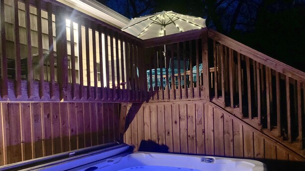 A hot tub with a wooden deck and railing, surrounded by a fence. - Quiet Mid-Mod Getaway with Hot Tub, Outdoor Seating & Firepit (Asheville)