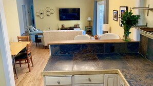 A modern living room with a sofa, TV, and a dining area with a table and chairs. - Quiet Mid-Mod Getaway with Hot Tub, Outdoor Seating & Firepit (Asheville)