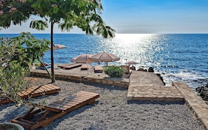 Privat strand i nÀrheten, svart sandstrand, solstolar och parasoller