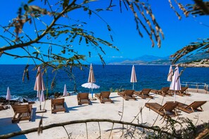 A beach with wooden lounge chairs and umbrellas, a clear blue sky, and the sea in the background. - Limunada Apartments (Utjeha)