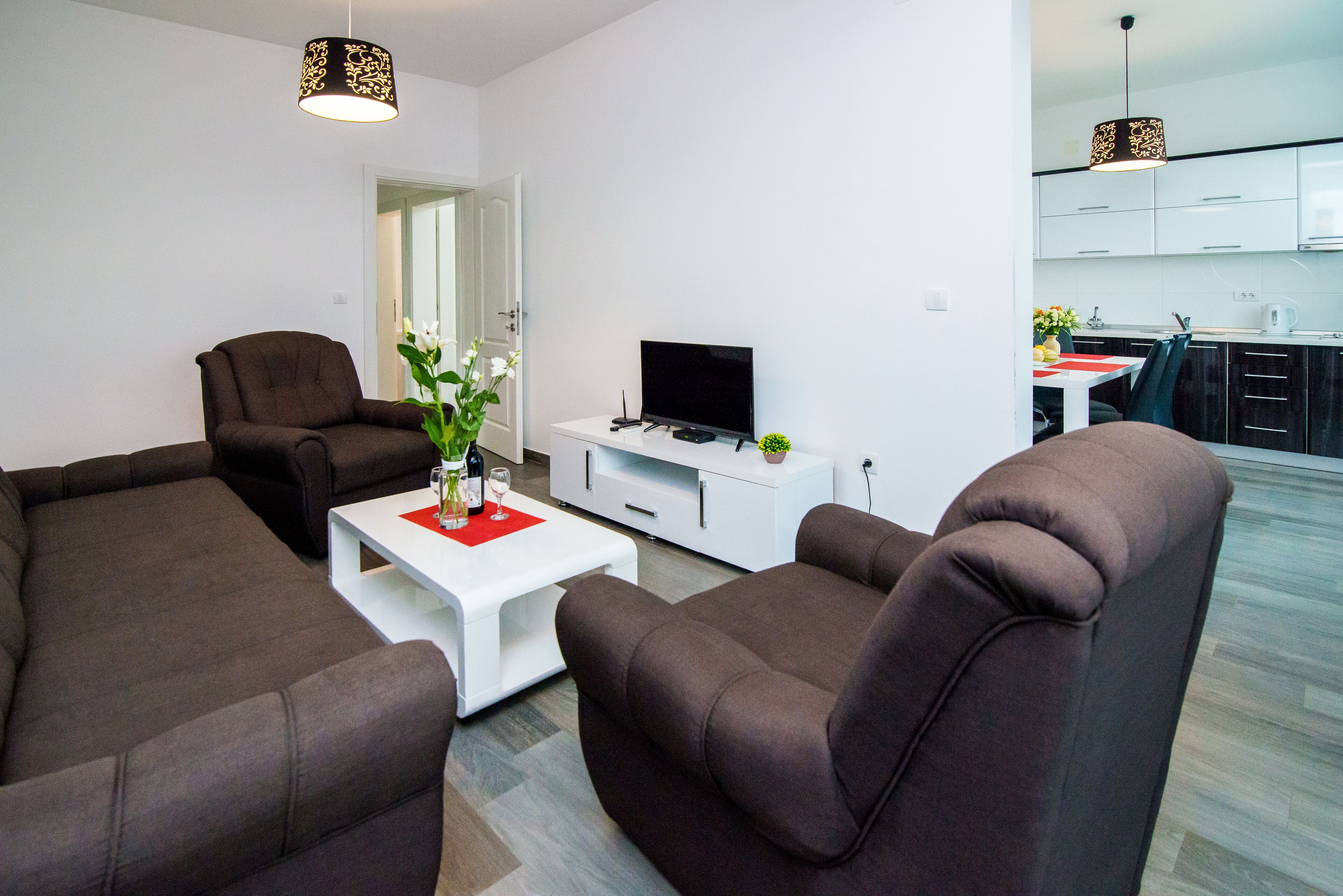 A modern living room with a sofa set, a flat-screen TV, and a white coffee table.