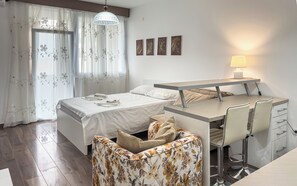 A modern bedroom with a bed, a desk, and a chair. - Limunada Apartments (Utjeha)