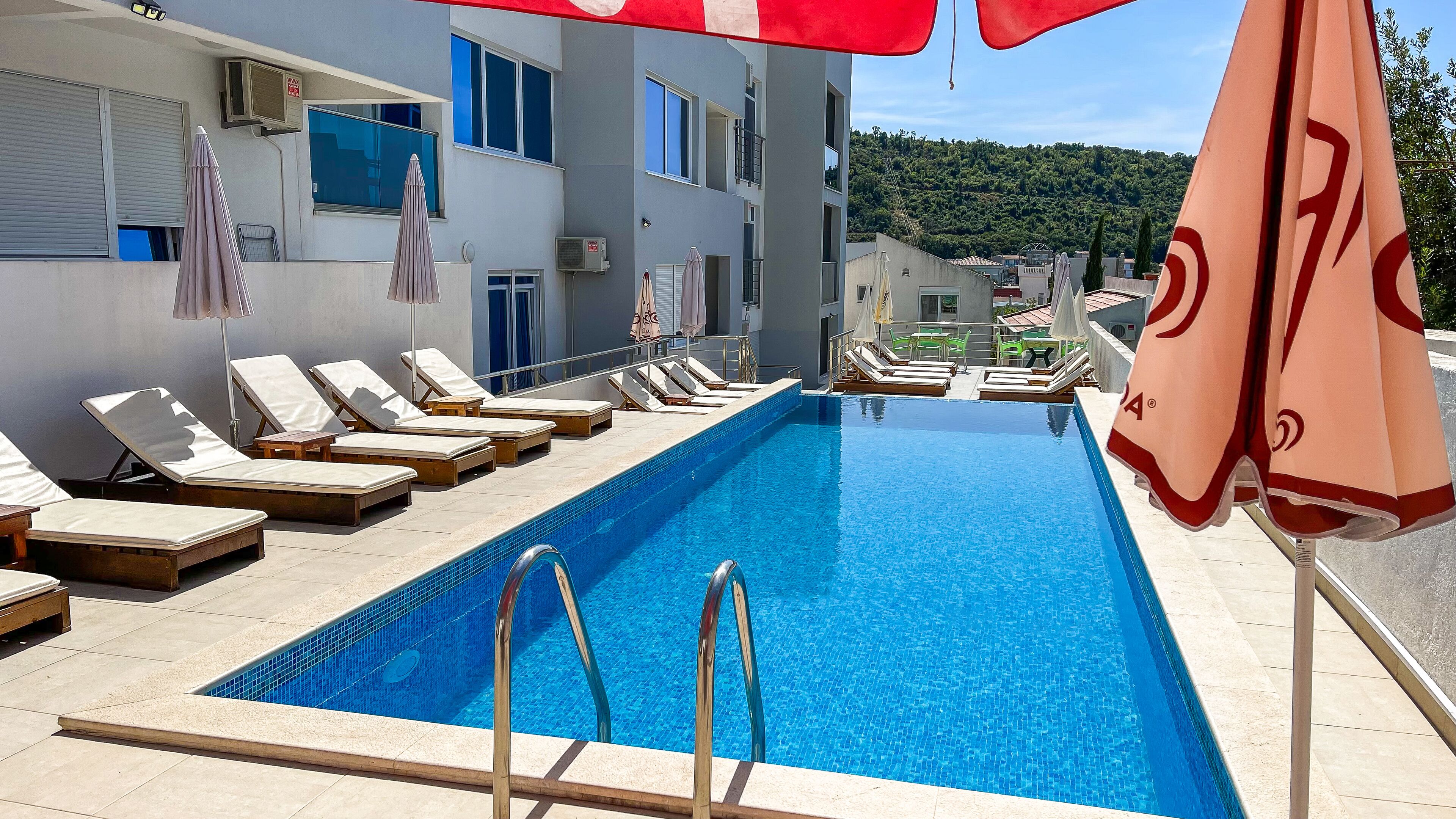 En säsongsöppen utomhuspool, parasoller och solstolar