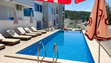 En säsongsöppen utomhuspool, parasoller och solstolar