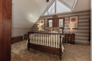 A bedroom with a sloped ceiling, a wooden bed, two bedside tables with lamps, and a dresser. - Moondust Lodge  - Sleeps 8 - Wrap Around Porch - Community Pool (Deep Gap)