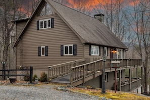 A two-story house with a wooden deck and a staircase leading to the upper level.