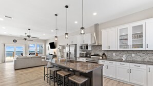 A modern kitchen with white cabinets, a granite island, and pendant lighting.