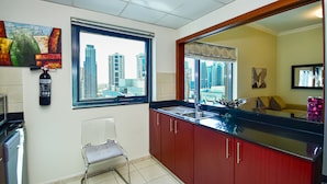 A compact kitchen with a window, a microwave, a chair, and a red cabinet. - Budget 1BR Apt in Marina  -Time (Dubai)