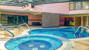 An indoor swimming pool with a glass ceiling, a reception area, and a seating area. - Budget 1BR Apt in Marina  -Time (Dubai)
