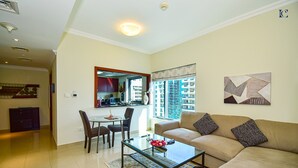 A modern living room with a glass coffee table, beige sofa, and a dining area with chairs and a small table. - Budget 1BR Apt in Marina  -Time (Dubai)