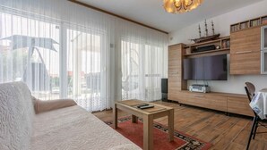 A modern living room with a sofa, a coffee table, a TV, and wooden cabinets.