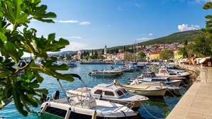 A marina with various boats docked, a town in the background, and a clear sky.