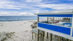 Ett hus vid stranden med pool och utomhusmöbler.