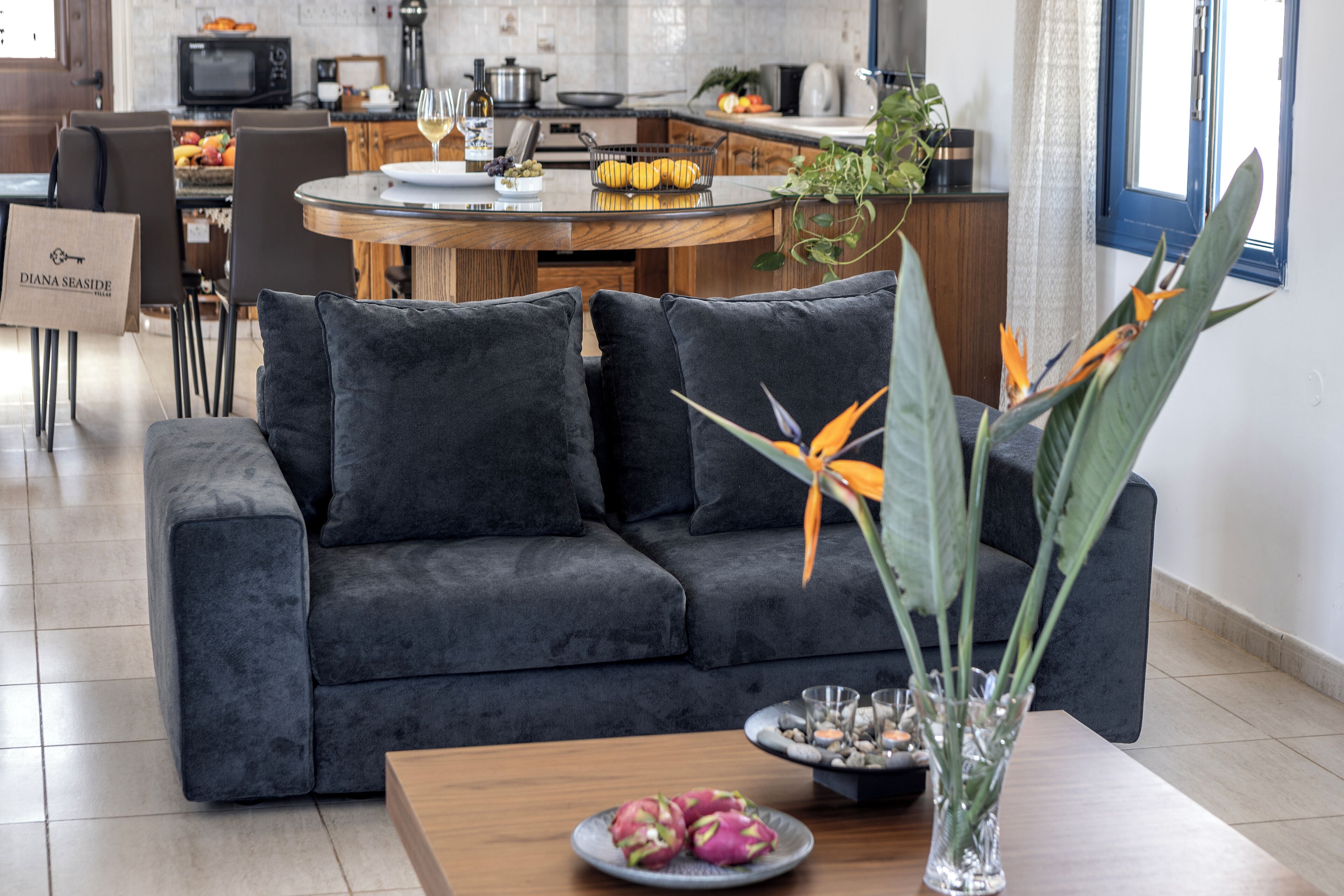 A modern living room with a dark grey sofa, a wooden coffee table, and a vase with flowers.