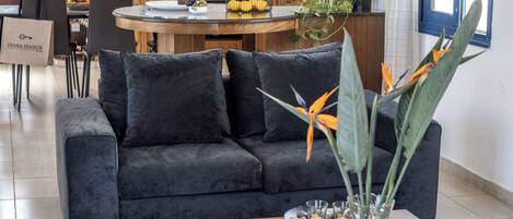 A modern living room with a dark grey sofa, a wooden coffee table, and a vase with flowers.