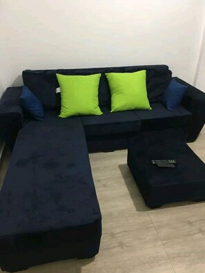 Ein dunkelbraunes Sofa mit zwei hellgrünen Kissen und passendem Fußhocker.