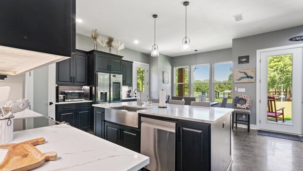 A modern kitchen with dark cabinets, stainless steel appliances, and a large island. - Richland Chambers Lakefront 2-story home with boat dock and pavilions. (Streetman)