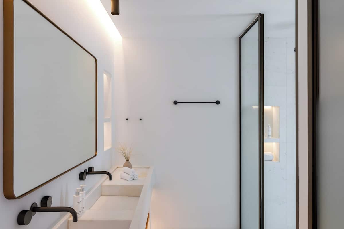A modern bathroom with a large mirror, a sink, a towel rack, and a shower area.
