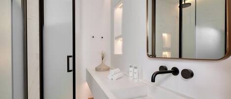 A modern bathroom with a large mirror, a white sink, and a shower area.