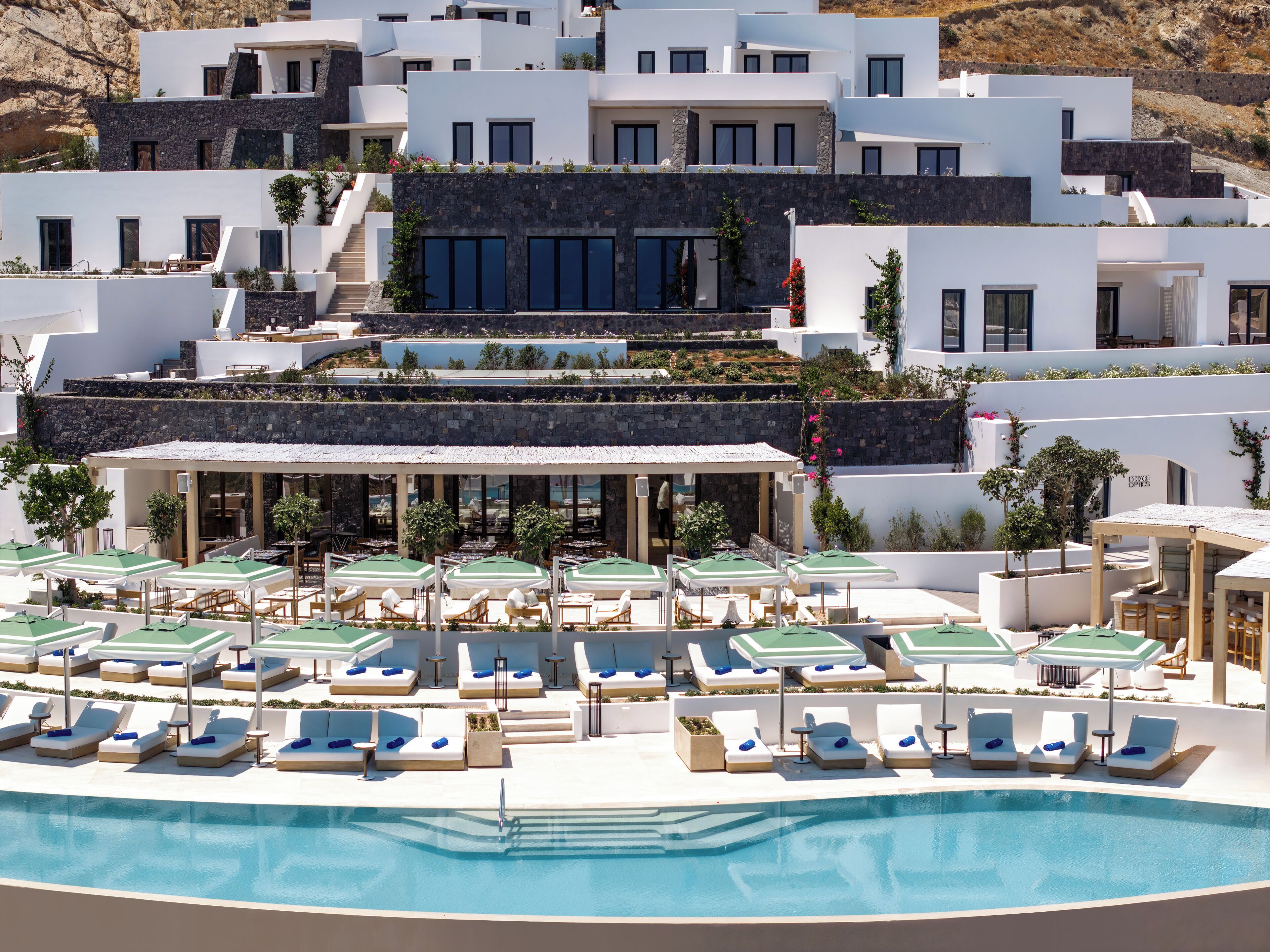 Ein modernes Resort mit Poolbereich, Liegestühlen und einem Restaurant mit Außenbereich.