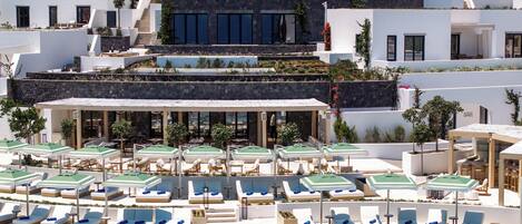 A modern resort with a pool area, sun loungers, and a restaurant with outdoor seating.