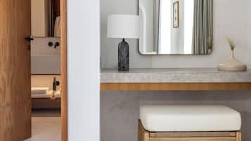 Un bagno con una panca in legno, un lavabo in marmo, uno specchio e un vaso con una pianta.