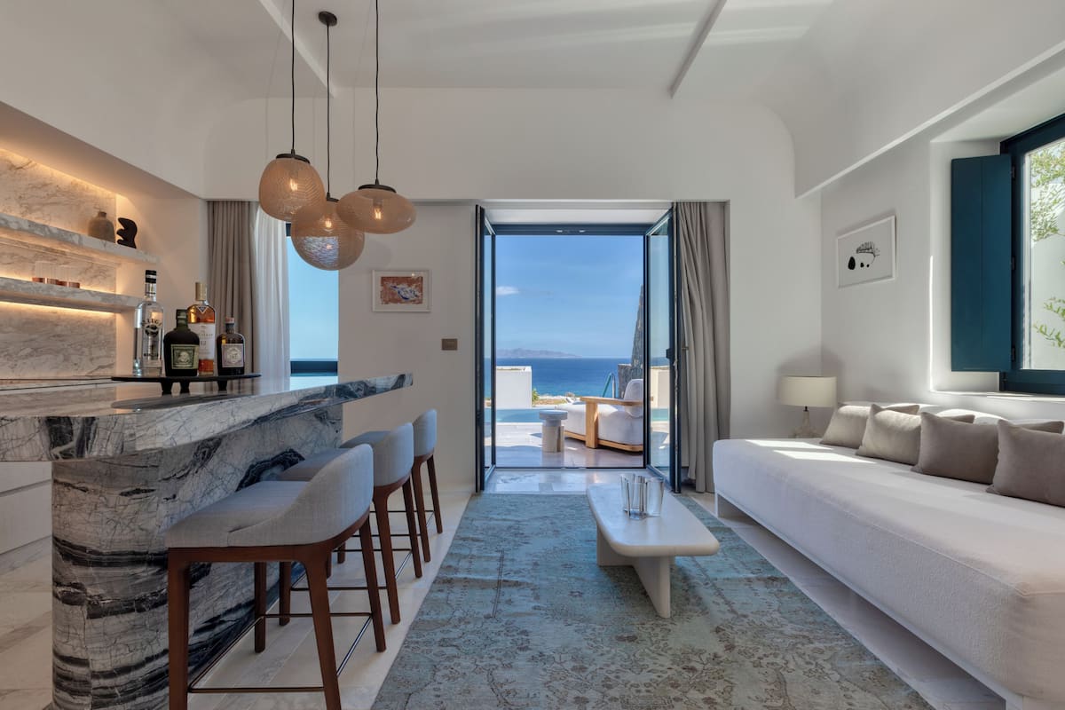 A modern living room with a marble bar, seating area, and a view of the sea.