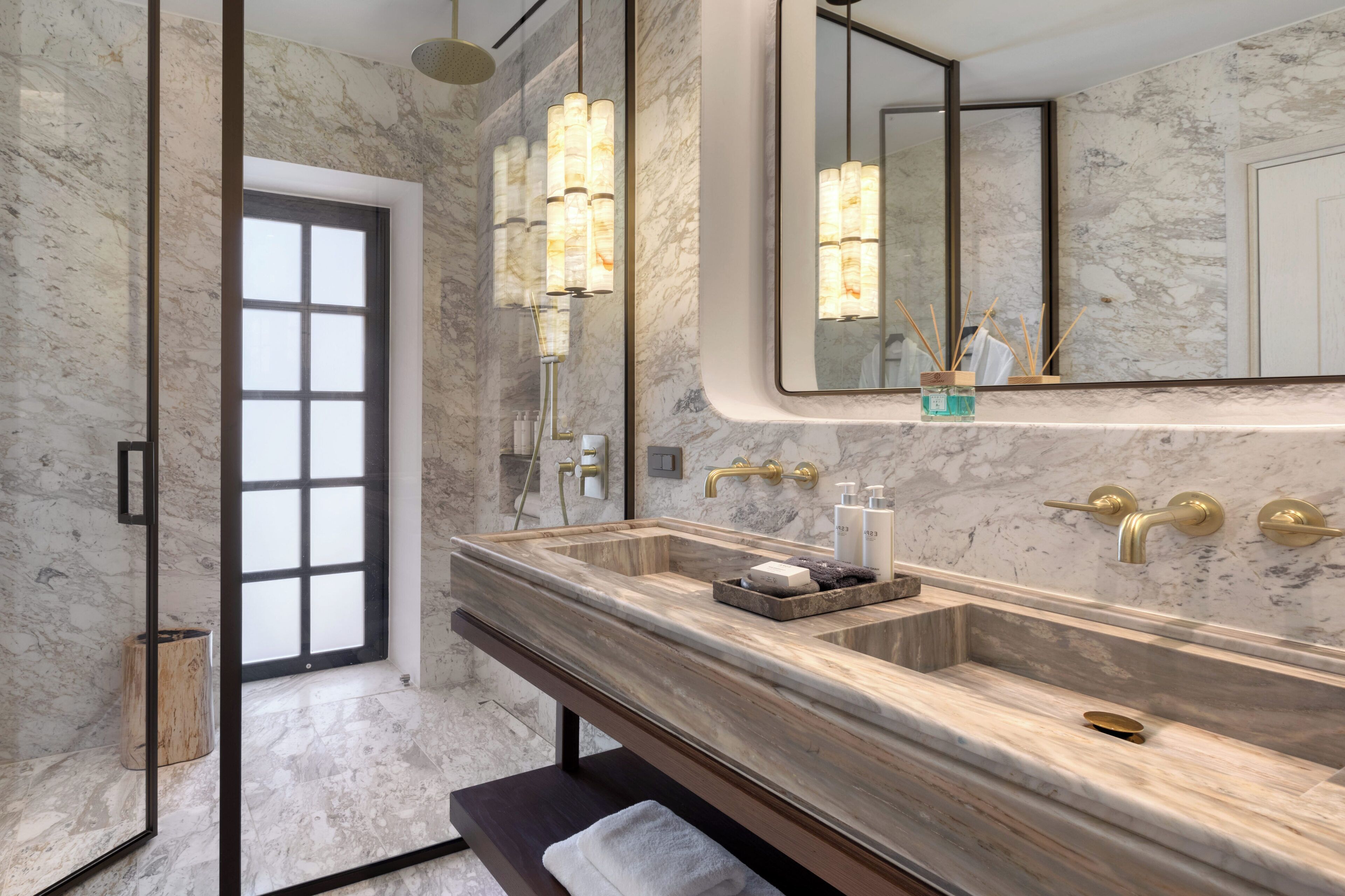 A modern bathroom with a large marble sink, a bench, and a large mirror.