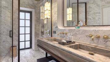 A modern bathroom with a large marble sink, a bench, and a large mirror.